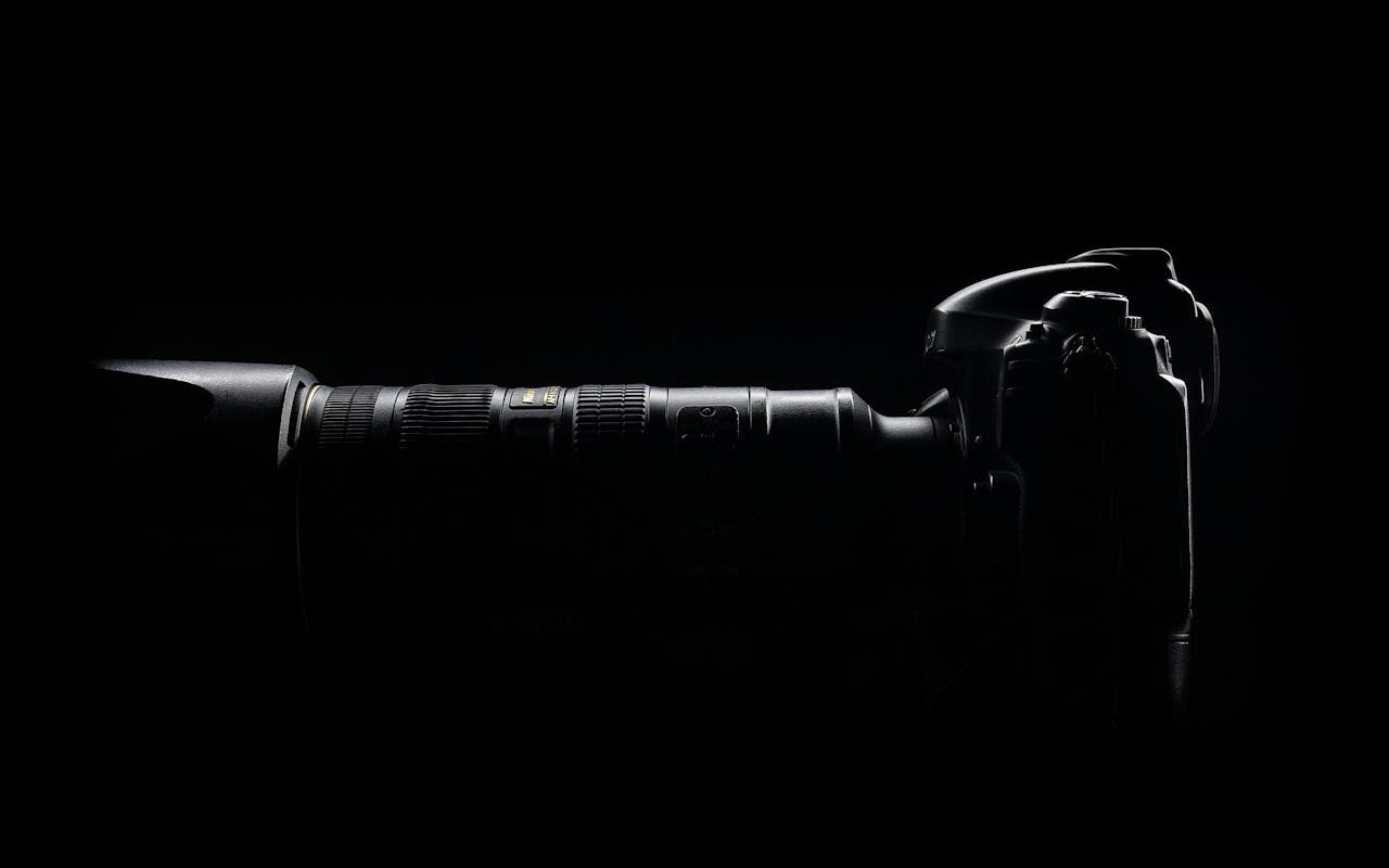 Artistic side profile of a DSLR camera with lens in dark setting.